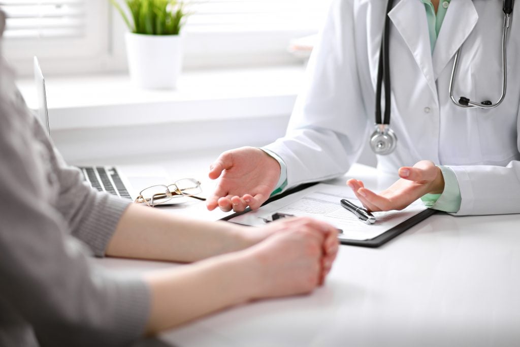 Close,Up,Of,Doctor,And,Patient,Sitting,At,The,Desk